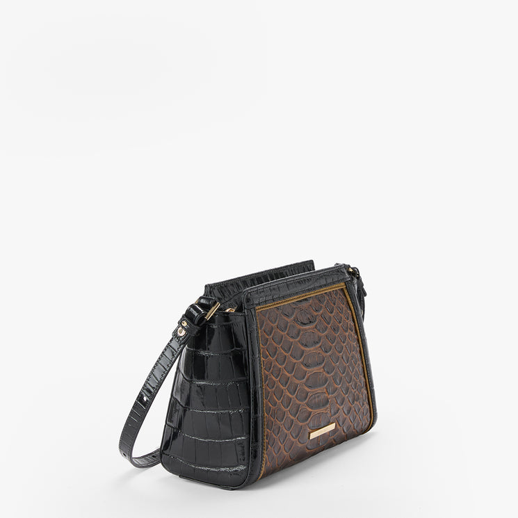 A structured shoulder bag with a black crocodile-embossed side and a brown textured front panel, featuring a gold-tone Brahmin plaque and a matching black shoulder strap, set against a plain white background.