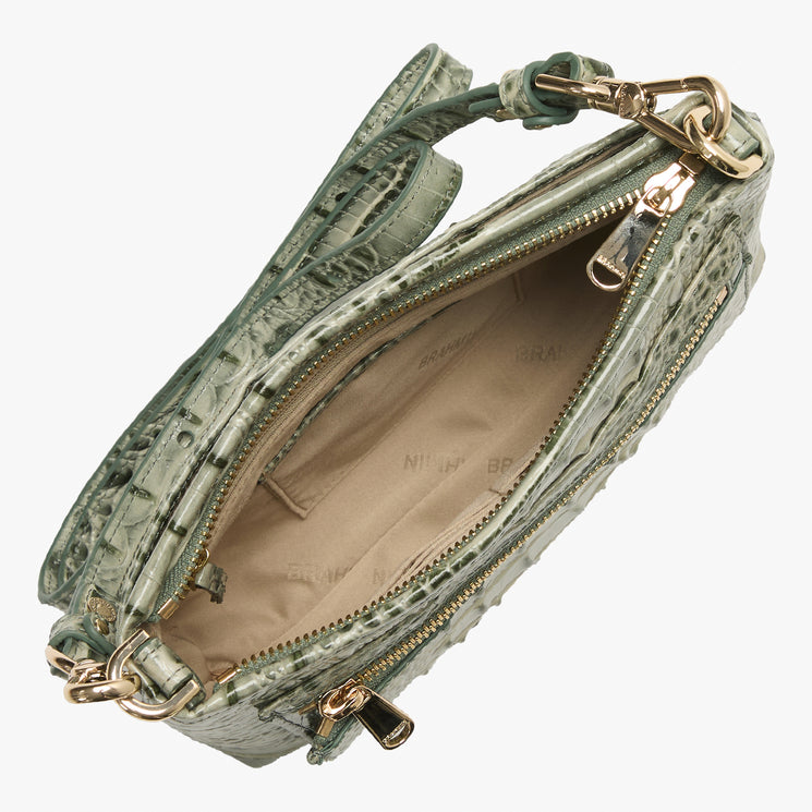 An open shoulder bag with a textured crocodile-embossed leather exterior in sage green, showing a beige interior lining and gold-tone hardware, photographed on a light gray background.