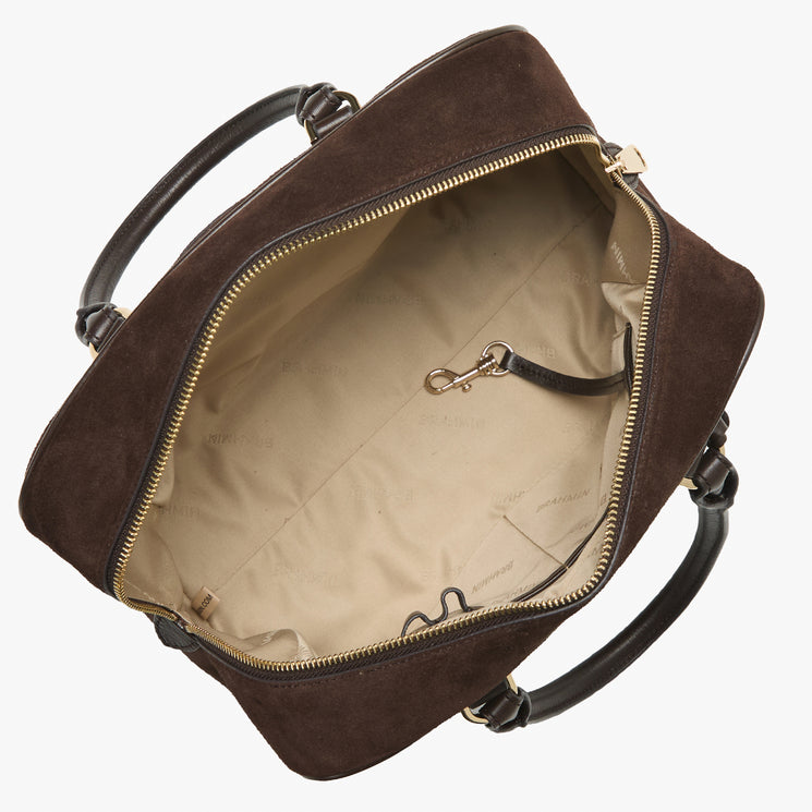An open dark brown suede duffel bag with brown leather handles and gold-tone zippers, showing a beige interior lining.