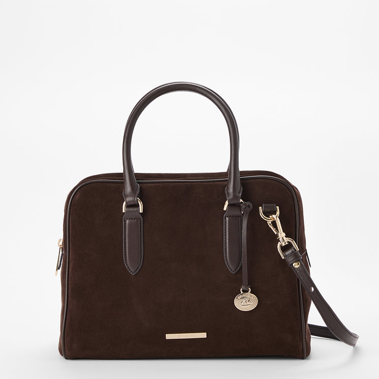 A dark brown suede satchel bag with dark brown leather handles and a matching shoulder strap, featuring gold-tone hardware and a small round metal charm, shown on a plain white background.