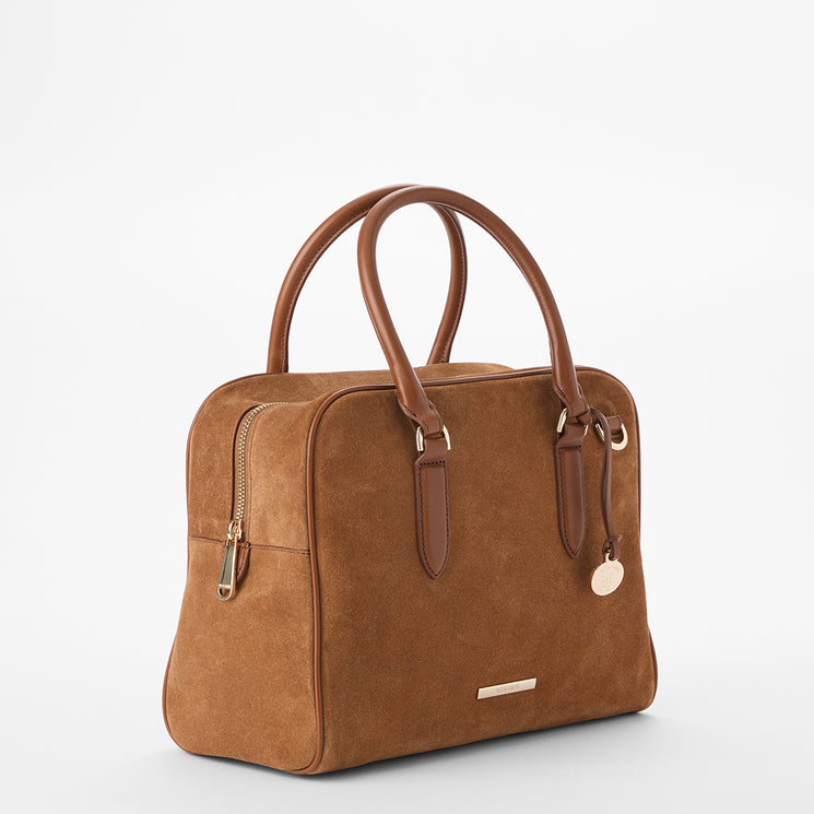 A structured brown suede handbag with dual top handles, a zippered side pocket, and gold-tone hardware, photographed on a clean white studio background.