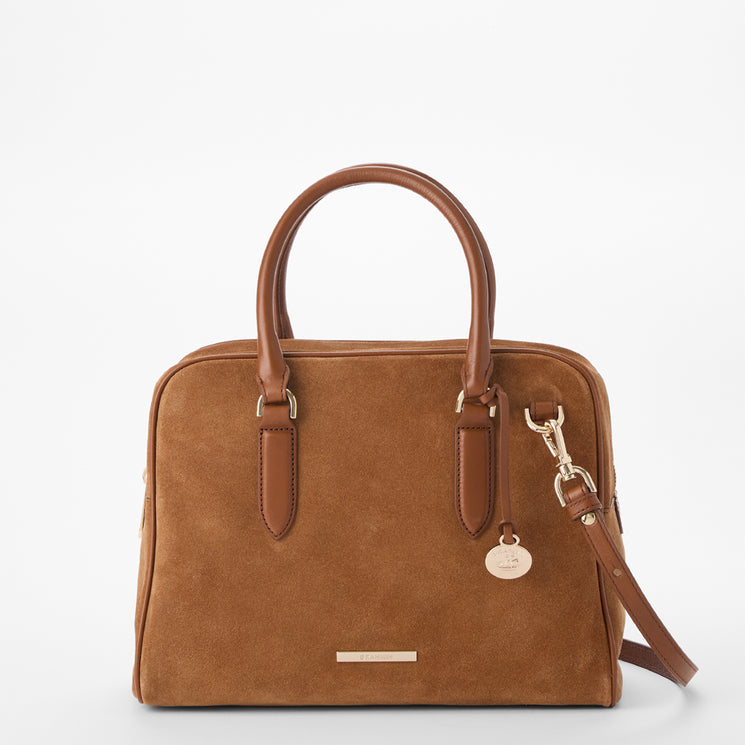 A structured brown suede handbag with brown leather handles and trim, featuring a gold-tone metal charm and a matching shoulder strap, set against a plain white background.