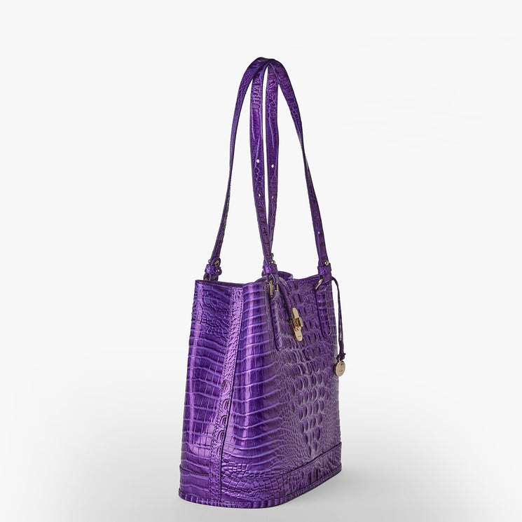 Brahmin purple embossed leather handbag featuring two shoulder straps, gold-tone hardware, a small round charm, and a textured finish, displayed against a plain white background.