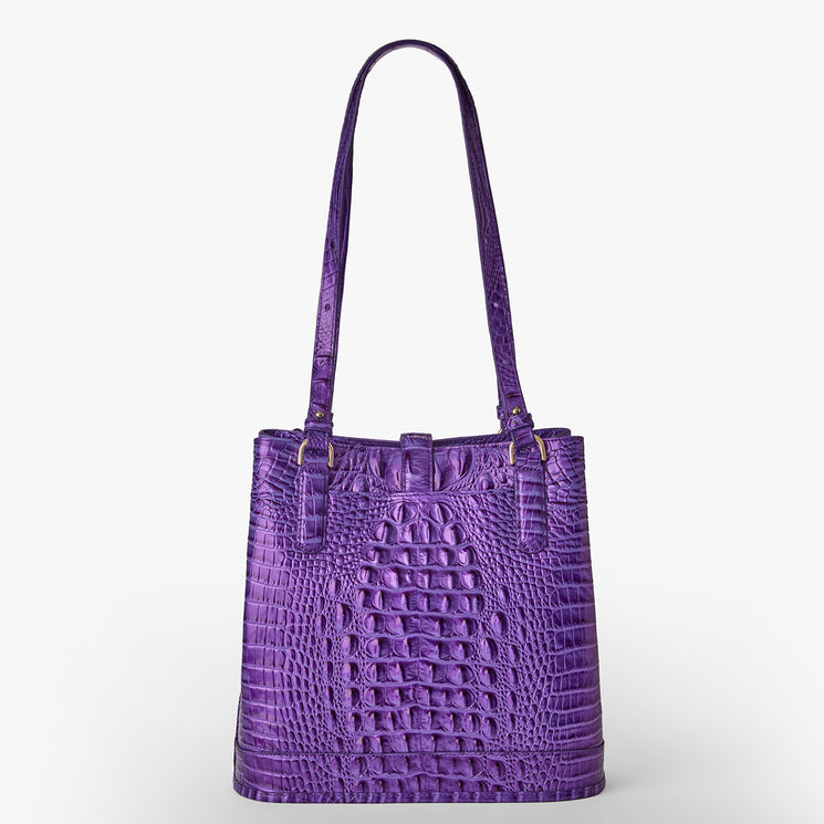 Brahmin handbag in purple with embossed crocodile-inspired pattern, rectangular silhouette, two long shoulder straps, gold-tone hardware; shown against white background. Perfect as a statement shoulder bag.