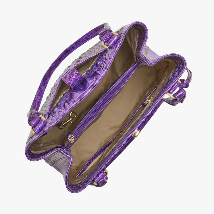 Brahmin purple embossed handbag with gold hardware, structured silhouette, dual top handles, visible compartments, center zip pocket, tan lining, inner side zip pocket, key clip; front angle view.