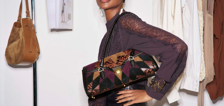 Model wearing Dayan handbag in brown snake skin, black suede, and purple suede detailing across the bag