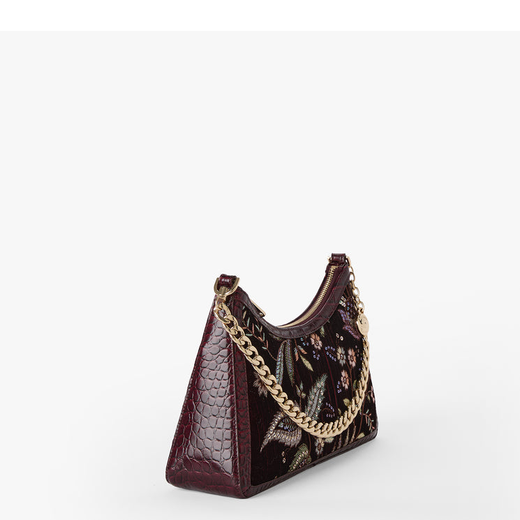 A dark burgundy hobo shoulder bag with textured crocodile-embossed leather panels, a floral body, and a gold-tone chain strap, shown on a plain white background.