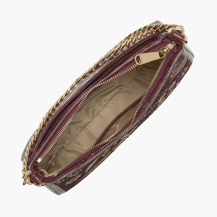 An open top view of a dark burgundy clutch bag with a gold chain strap and gold zipper, showing a beige interior lining, set against a plain light gray background.