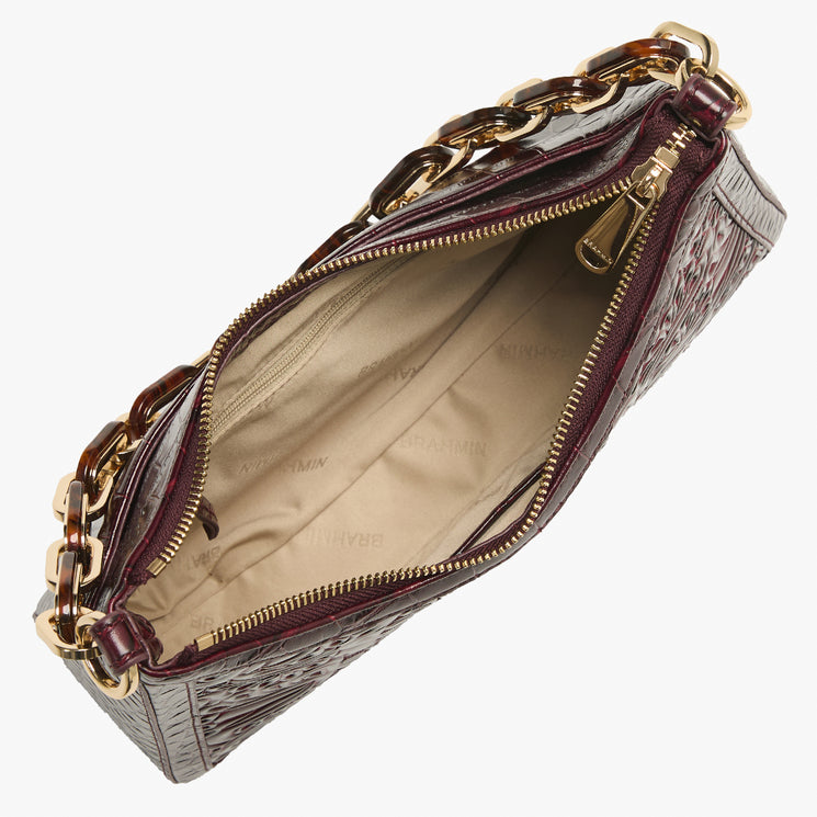 A top-down view of a dark burgundy crocodile-embossed leather handbag with gold-tone chain and zipper details, showing a beige interior lining with faint 'BRAHMIN' branding.