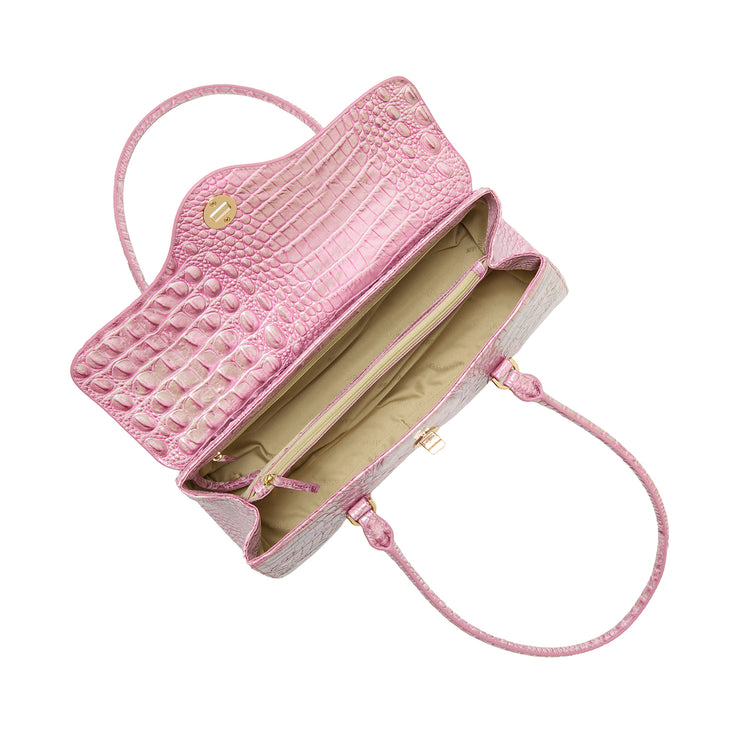 Brahmin pink embossed leather satchel with gold clasp, open to reveal beige interior, zipper pocket, and dual top handles. Bag shown on a white background with visible textured pattern and structured shape.
