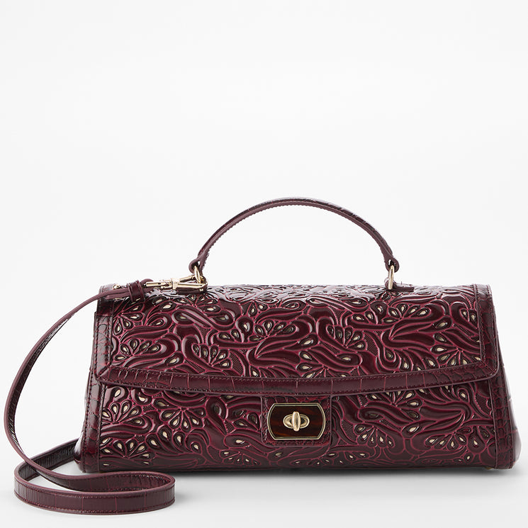 A burgundy embossed leather handbag with a top handle, shoulder strap, and gold-tone turn-lock closure, shown on a light gray background.