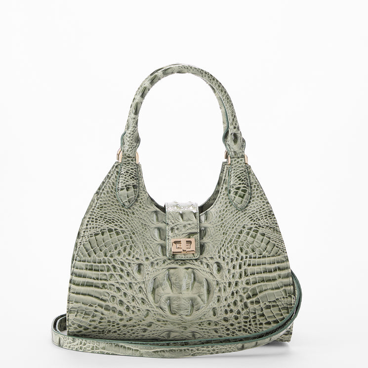 A structured shoulder bag made of textured crocodile-embossed leather in a muted sage green, featuring dual top handles, a central clasp closure, and a matching shoulder strap, shown against a plain white background.