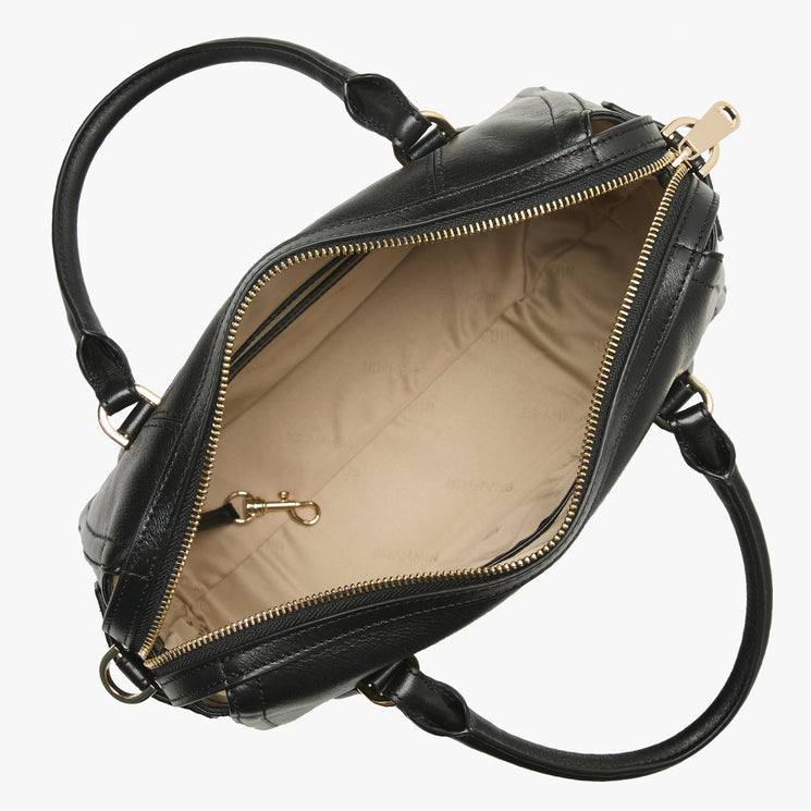 Brahmin black quilted handbag open top view, beige interior lining with gold-tone zipper pocket and key clip. Dual top handles, detachable shoulder strap attachments, and textured pattern visible.