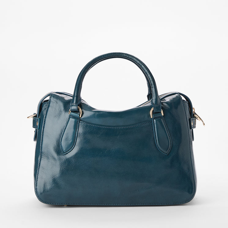 Brahmin handbag in shiny teal leather with dual top handles, gold-tone hardware, and a structured silhouette. Simple design, smooth texture, shown upright against a plain white backdrop.