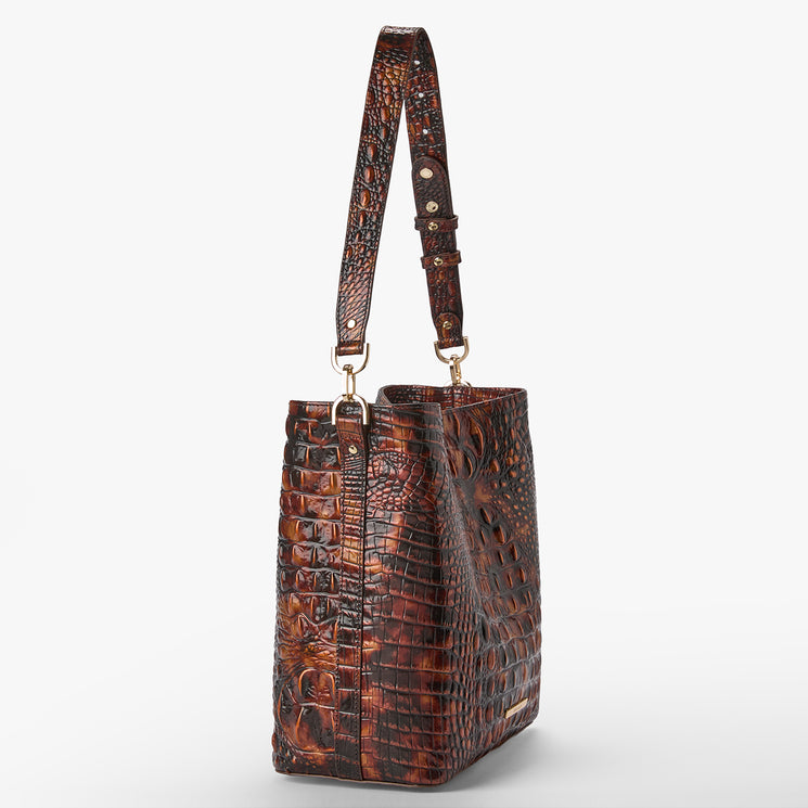 A brown crocodile-embossed leather tote bag with a single shoulder strap and gold-tone hardware, shown against a plain light gray background.