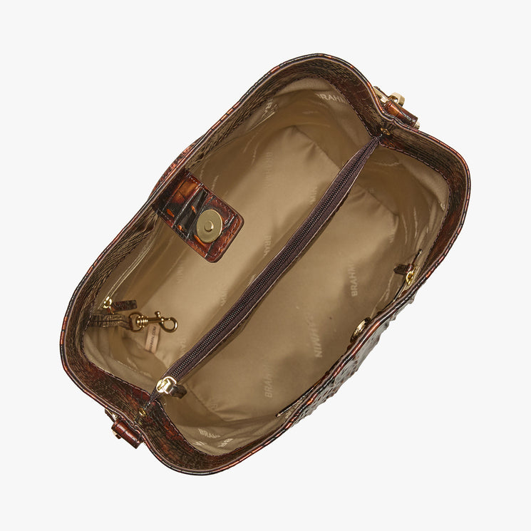An overhead view of an open brown textured handbag showing its beige interior lining, zippered compartments, and gold-tone hardware against a light gray background.