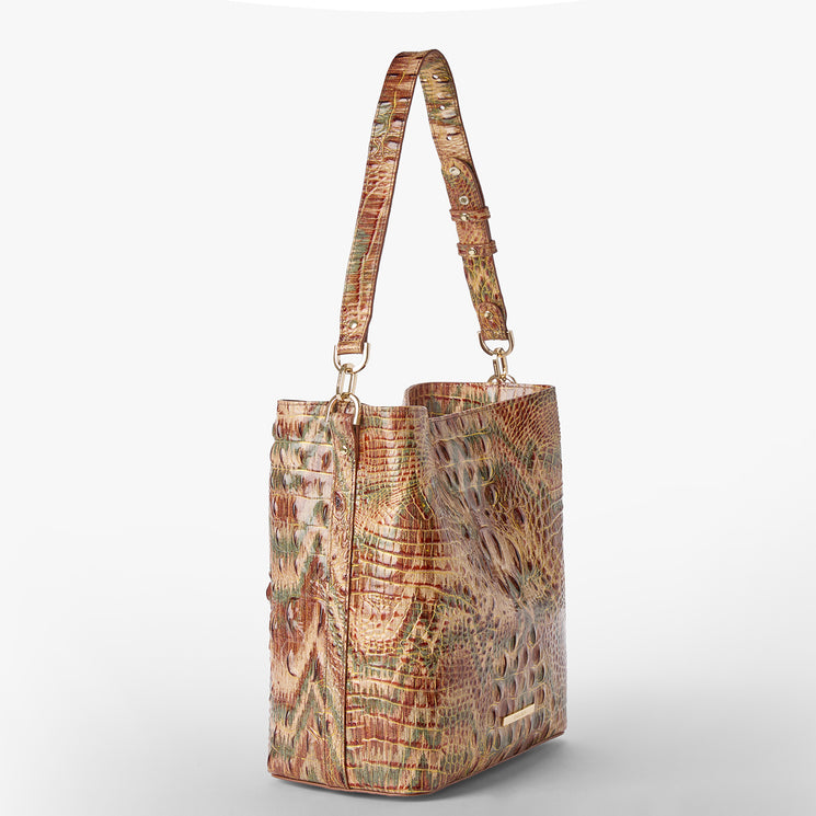 A shoulder bag with a textured crocodile skin pattern in shades of brown, beige, and muted green, featuring a gold Brahmin plaque on the front. Celina Side View.