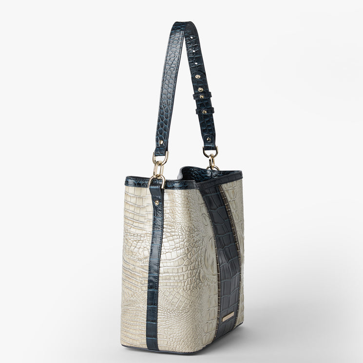 Brahmin structured handbag with a textured cream body, navy blue vertical stripe accents, matching adjustable navy blue shoulder strap, gold-tone hardware, and rectangular silhouette shown on a white background.
