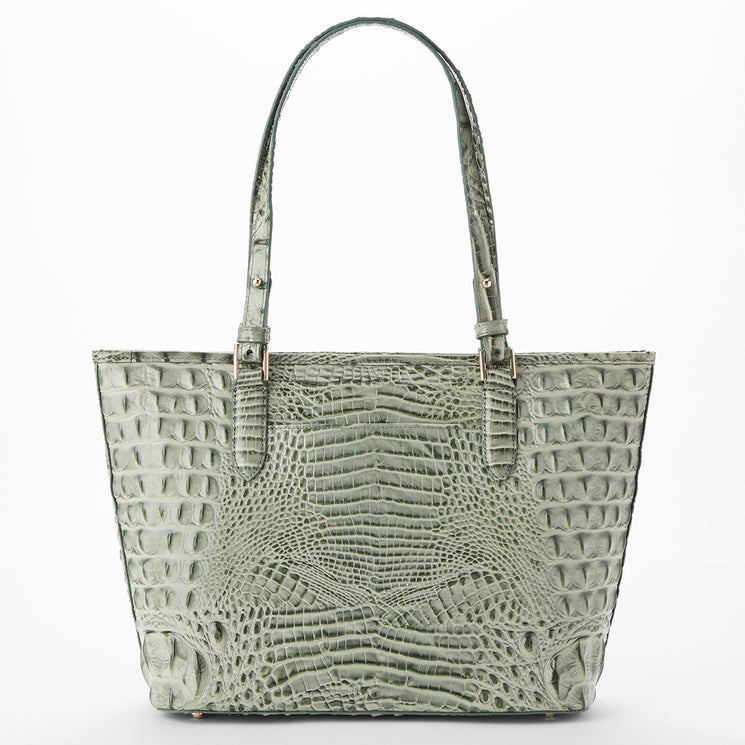 A structured tote bag with a crocodile-embossed texture in sage green, featuring dual top handles and gold-tone hardware, set against a plain white background.