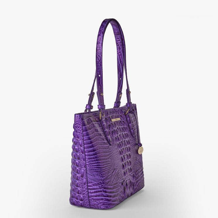Brahmin purple tote bag with an embossed textured pattern, double top handles, gold-tone hardware, and a round hanging tag. Presented against a white background for clear product viewing.