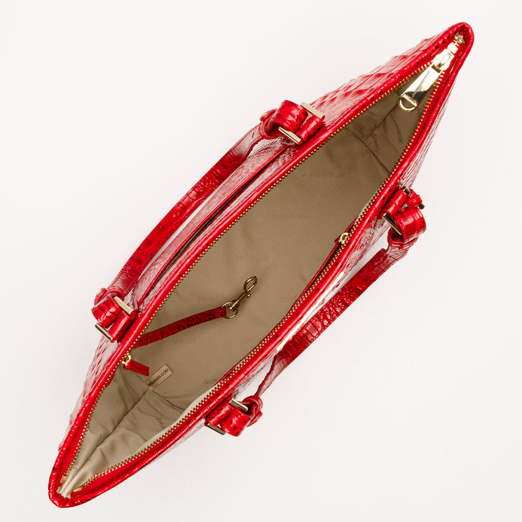 Top-down view of a glossy, embossed red Brahmin Medium Asher tote. Features gold-tone hardware, two top handles, and a beige fabric-lined interior with a lobster-claw key clip.
