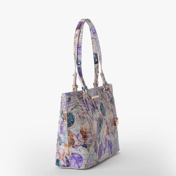 Brahmin structured satchel with double top handles, abstract floral and textured pattern in purple, blue, and beige on white. Features gold-tone hardware and a flat base. Bag shown from the front view.