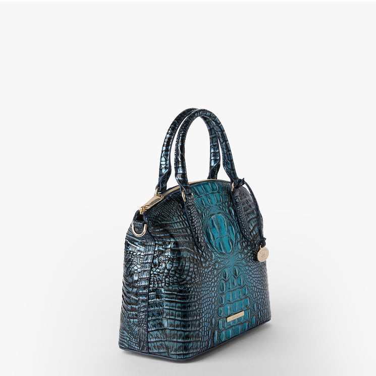 Brahmin handbag in teal and black with embossed textured pattern, gold hardware, two top handles, structured silhouette, and shown on a plain white background. No interior or strap details visible.