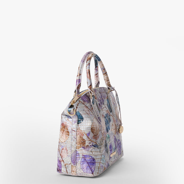 Brahmin structured handbag with a pastel floral print, gold-tone hardware, dual top handles, and an angled silhouette against a white background; features a classic shape ideal for hand or arm carry.