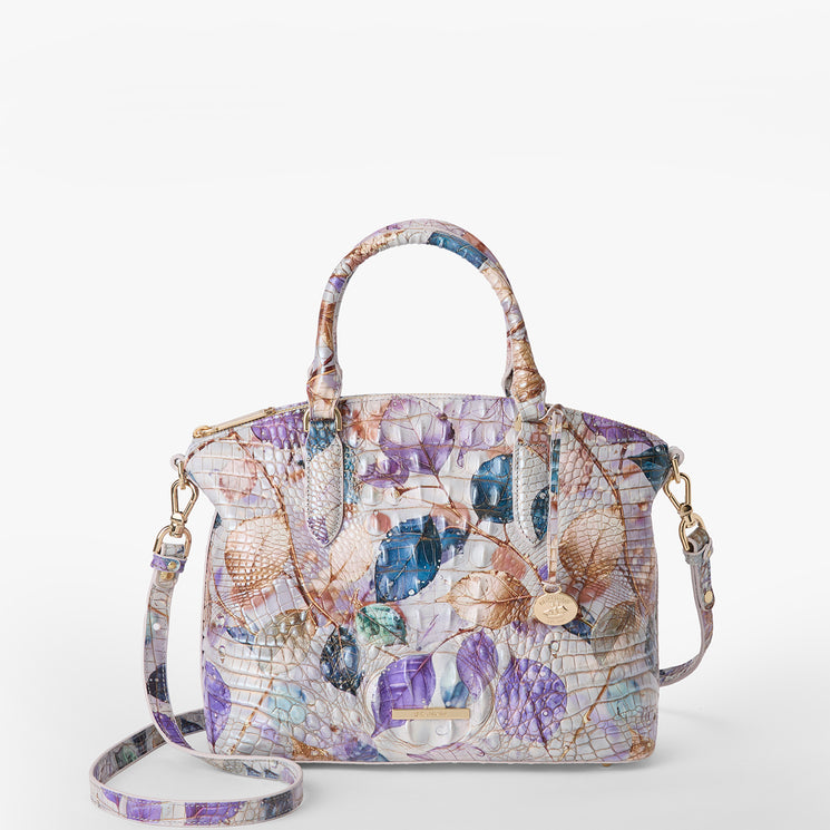Brahmin structured satchel in an embossed texture, displaying pastel purple, blue, and tan color-block design with gold hardware, dual top handles, detachable shoulder strap; shown on a white background.