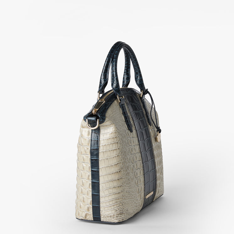 Brahmin structured satchel with embossed texture, cream side panels, dark top handles and trim, gold-tone hardware, a small logo plate at the bottom front. Handbag shown in classic silhouette with vertical accents.