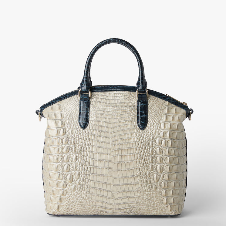 Brahmin structured handbag in ivory with embossed texture, dark navy handles, trim, and sides. Features gold-tone hardware and tote silhouette. Displayed on a plain white background, front view shown.
