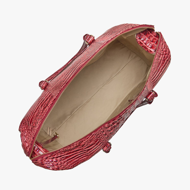 Brahmin red embossed duffel bag with gold-tone hardware, top zipper open to show spacious beige-lined interior, small side pockets, and double handles. Seen from above for clear view of inside details.