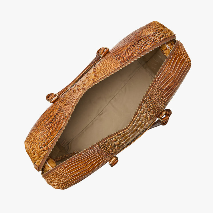 Open Brahmin brown embossed duffel bag with beige interior, top view. Features spacious interior, structured silhouette, textured pattern, gold-tone hardware, and dual handles on a white background.