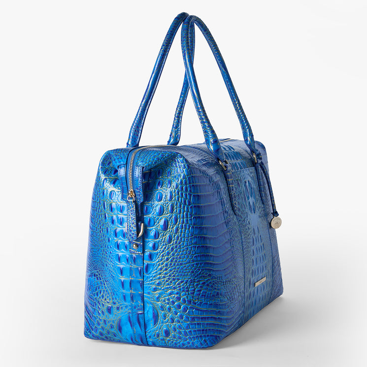 Brahmin handbag with structured silhouette, shiny blue embossed texture, dual long handles, gold-tone hardware accents, shown on white background. Suitable for shoulder or hand carry; exterior only visible.