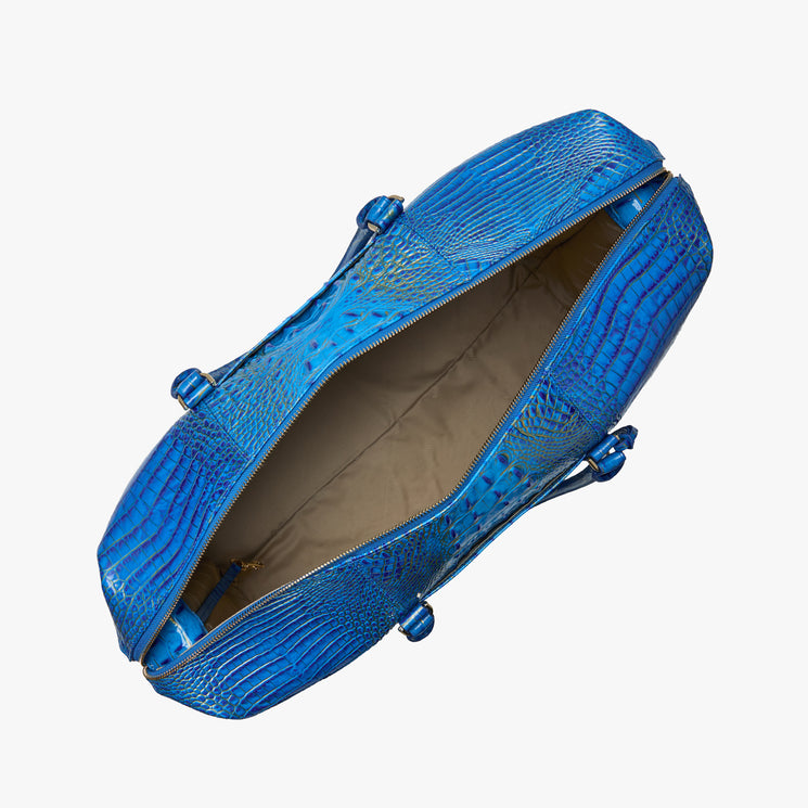 Brahmin blue textured leather handbag with embossed crocodile-inspired pattern, top view showing zipper open to reveal beige interior, no contents visible. Structured silhouette with elegant shape; handles not in frame.