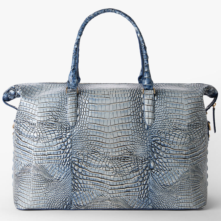 Brahmin satchel in bold blue with structured silhouette, two top handles, glossy embossed texture, and signature hardware. Displayed on a white background to highlight the bag’s color and croc-inspired pattern.