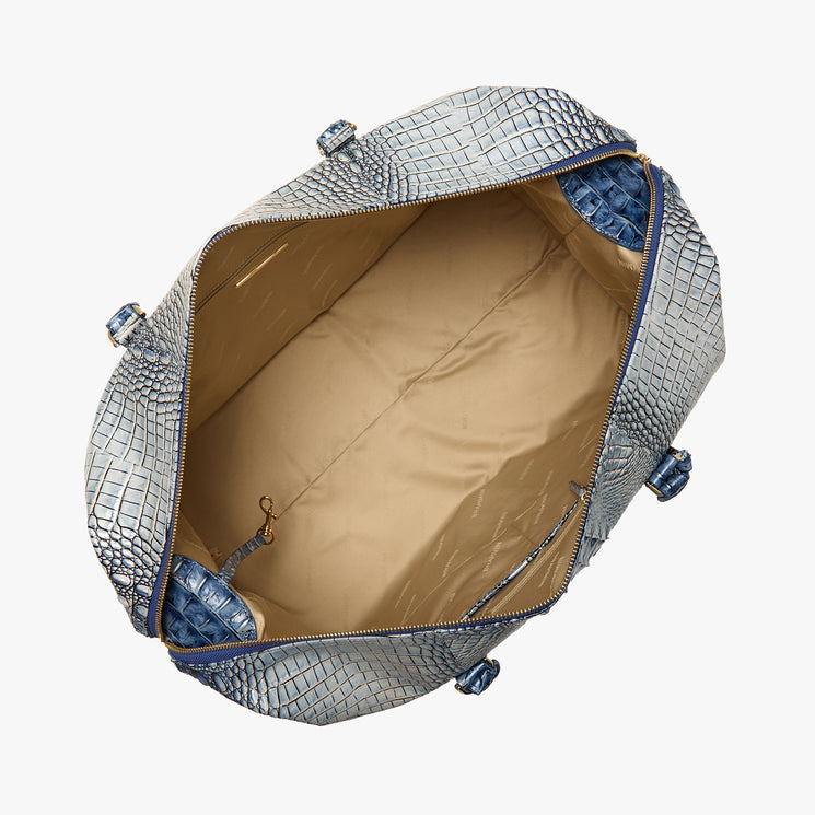 Brahmin blue embossed handbag with structured silhouette and gold-tone hardware, shown from above. Tan interior features side pockets and a key leash; bag is open to display spacious compartment.