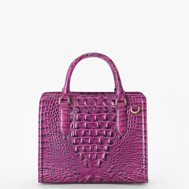 Brahmin purple embossed leather handbag with two top handles, gold hardware, and a structured rectangular silhouette, shown against a white background. Textured pattern enhances the distinctive look of this elegant bag.