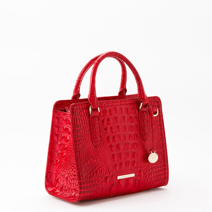 Brahmin Cami satchel in red with a glossy, croc-embossed texture. Features double top handles, gold-tone hardware, and a circular logo charm.
