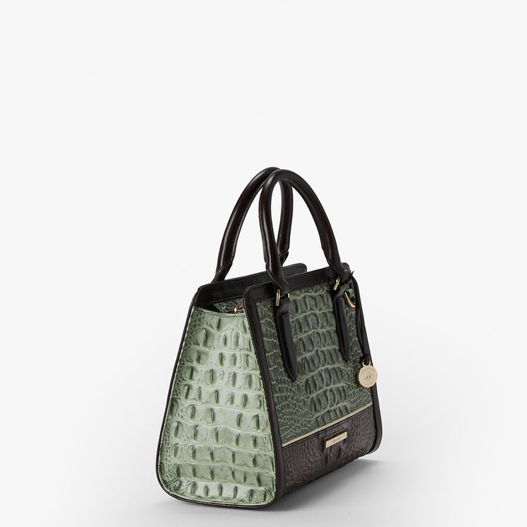 A structured handbag with a light green crocodile-embossed texture on the front and sides, contrasted with smooth black leather trim, double top handles, and gold-tone hardware.