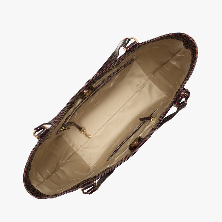 An overhead view of a dark red textured handbag showing its spacious beige interior with gold-tone hardware, set against a plain white background.