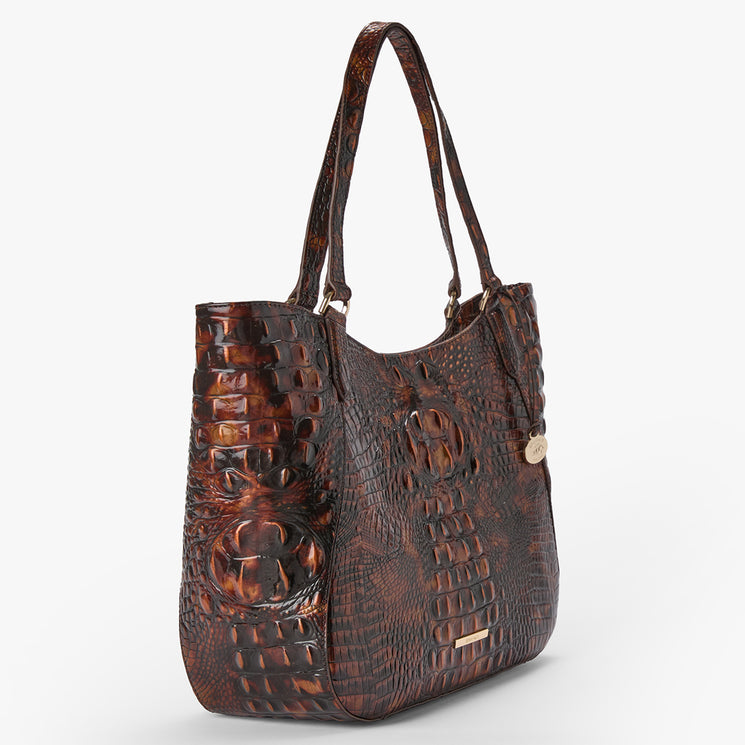A brown crocodile-embossed leather tote bag with dual shoulder straps and a small gold-tone logo charm, shown on a light gray background.