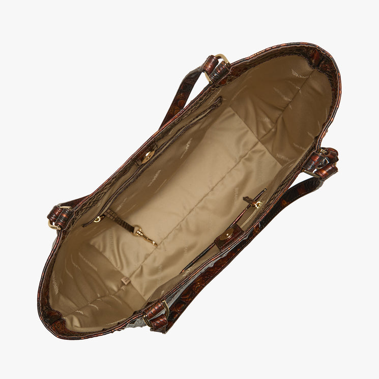 An overhead view of a brown textured handbag showing its beige satin-lined interior, straps, and gold-tone hardware against a light gray background.