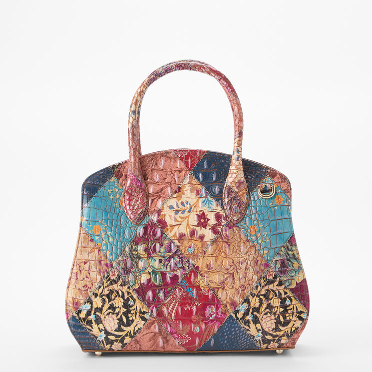 Brahmin patchwork satchel handbag with a textured finish and mixed floral, patterned, and solid panels in blue, red, gold, and pink. Features two rounded top handles and structured silhouette.
