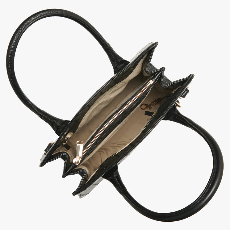 Top view of an open Brahmin black leather satchel with double handles, beige lining, central zippered pocket, key clip, and side compartments. Structured silhouette, silver-tone hardware. Bag is empty.