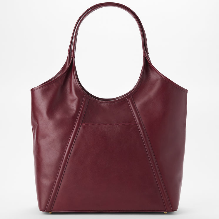 Brahmin large burgundy tote bag with a curved top, two shoulder straps, geometric seam details, smooth texture, and minimalist silhouette displayed against a white background. Bag is shown in upright front view.