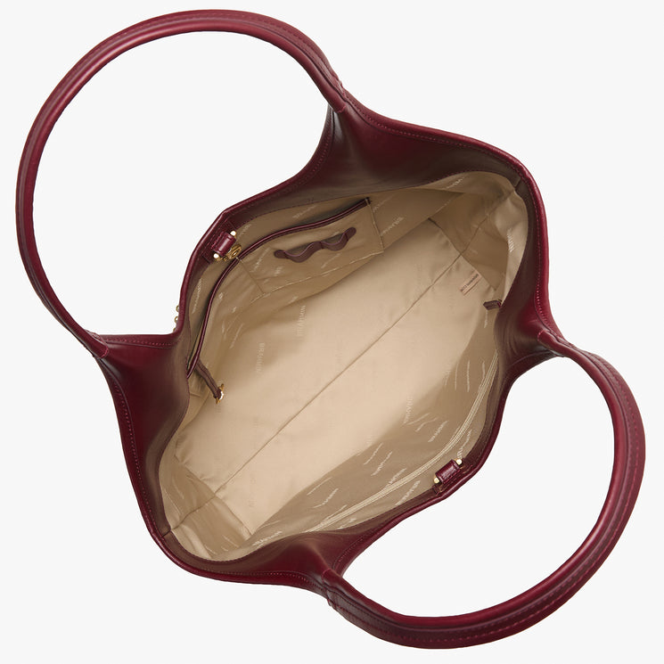 Top view of a Brahmin burgundy tote bag with a structured silhouette, beige interior, gold-tone hardware, a zippered pocket on one side, roomy open main compartment, and two flat shoulder straps.