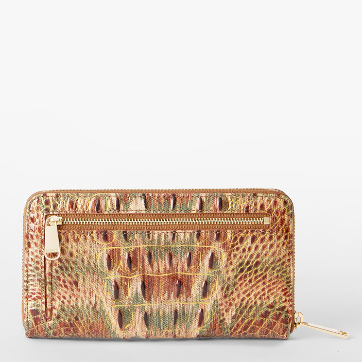 A zip-around wallet with a textured crocodile skin pattern in brown, beige, and green, featuring a gold Brahmin plaque and zipper pull. Suri Back View.