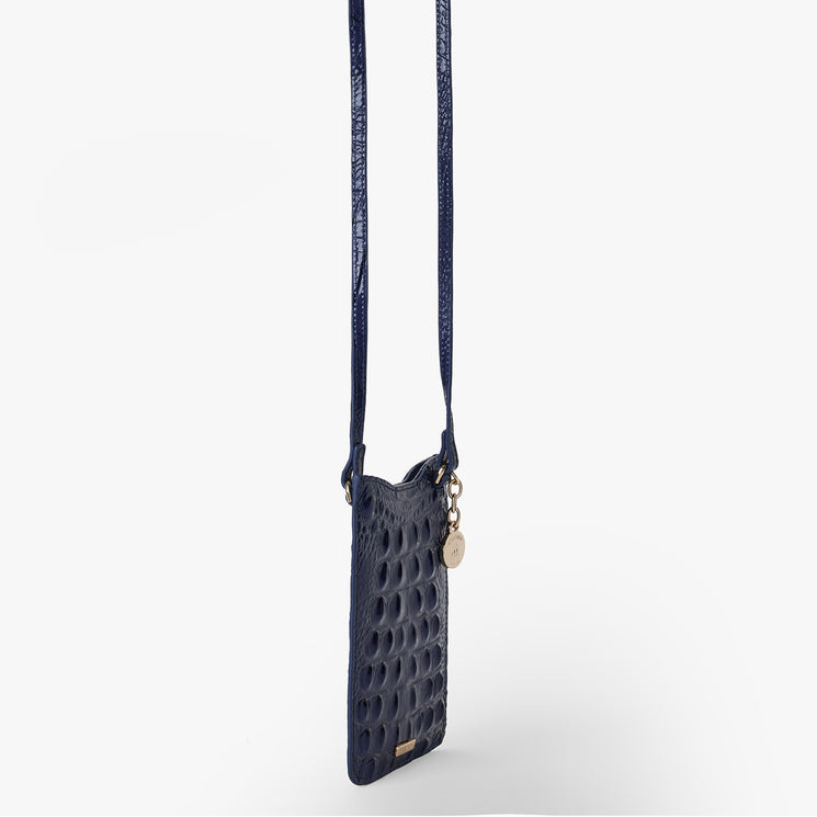 BRAHMIN Eris small midnight blue handbag with embossed texture, gold hardware, circular charm, and a long shoulder strap shown on a plain white background; can be worn crossbody as a phone pouch.