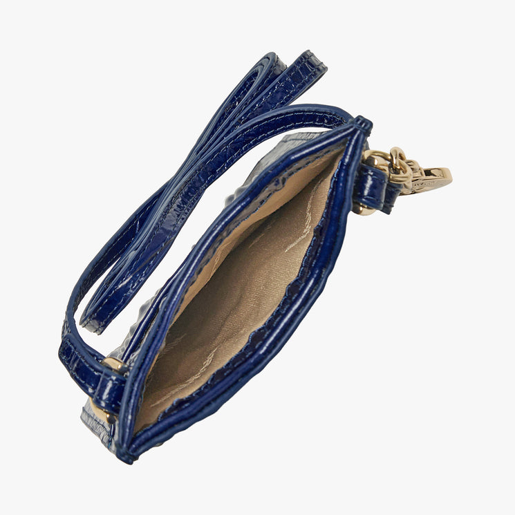 BRAHMIN Eris wristlet in midnight blue, small and open with a gold clasp, fabric-lined interior visible. Shown from above on a white background; compact silhouette works as a chic phone pouch or evening accessory.